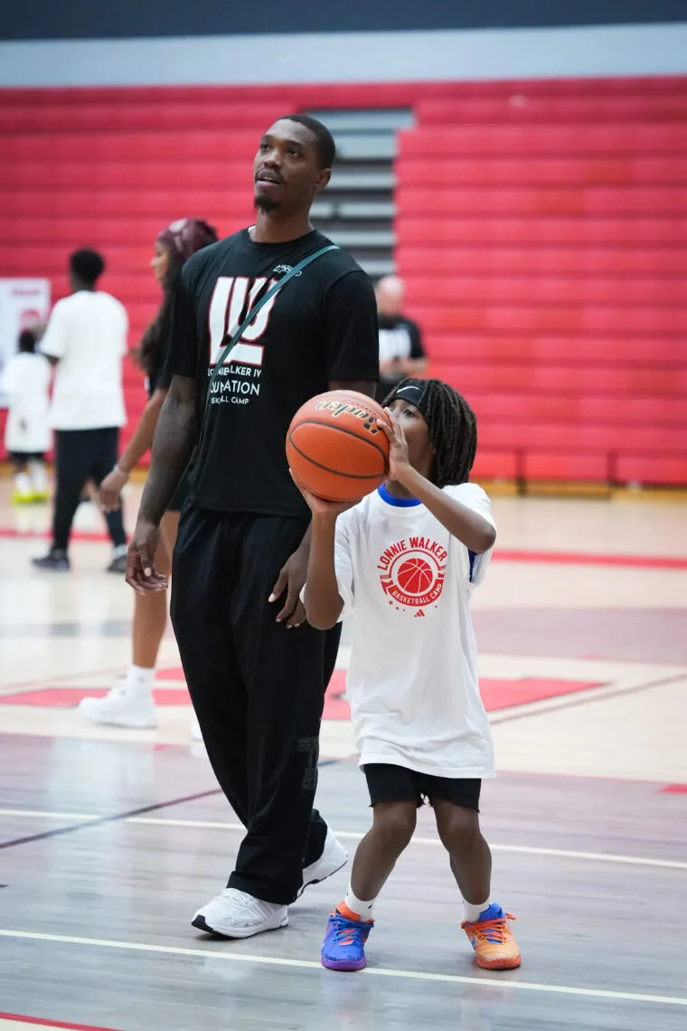 Lonnie Walker IV coaching a young camper on shooting form