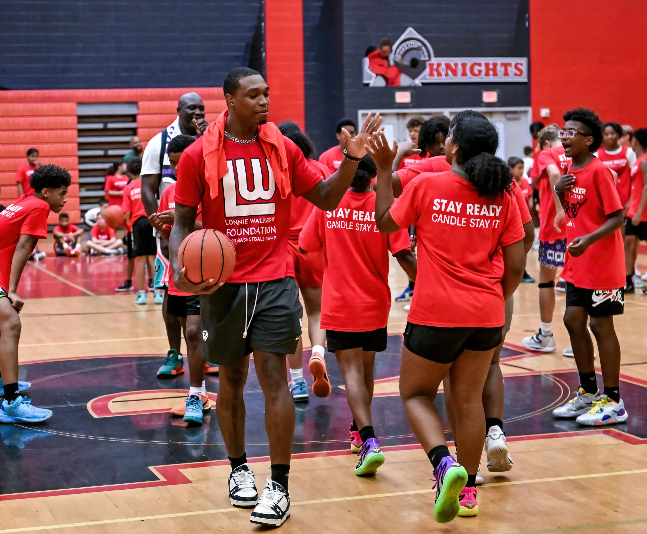 Lonnie Walker IV high-fiving campers at the Foundation&rsquo;s free youth basketball camp