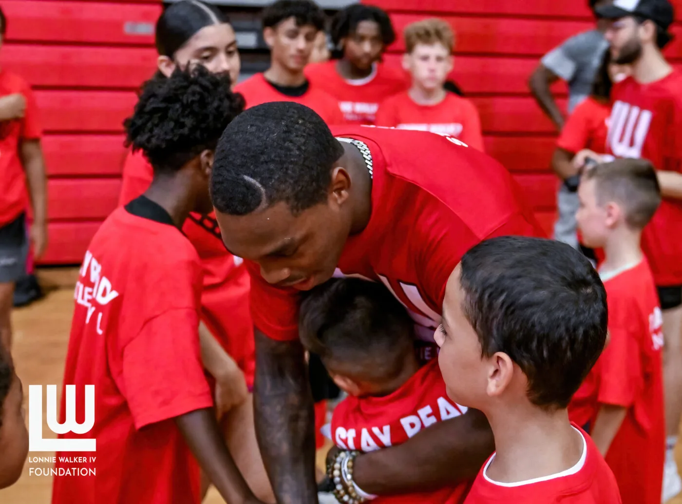 Lonnie Walker IV greeting campers in red Foundation camp shirts