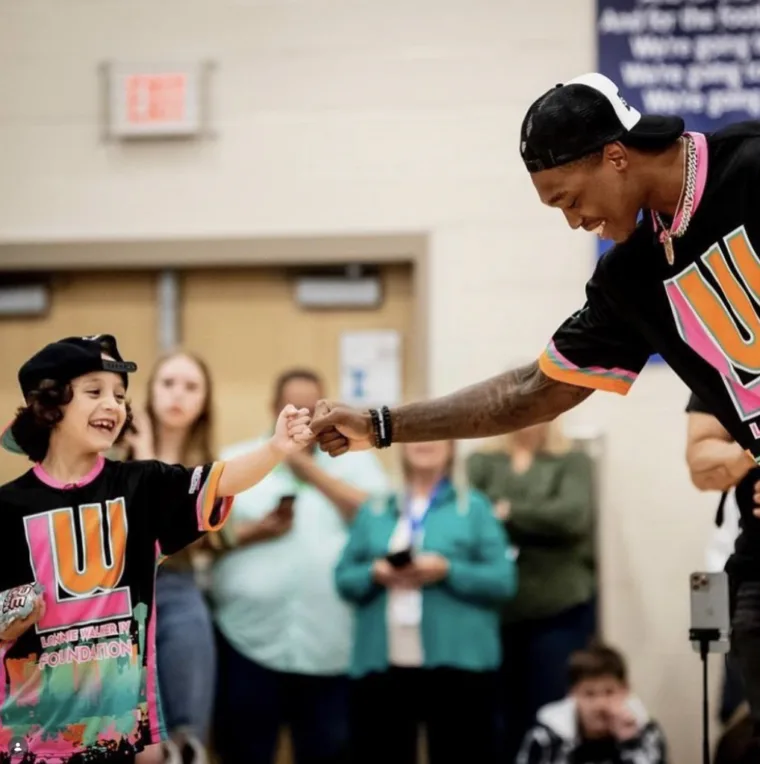 Lonnie Walker IV greeting a young fan at a community event