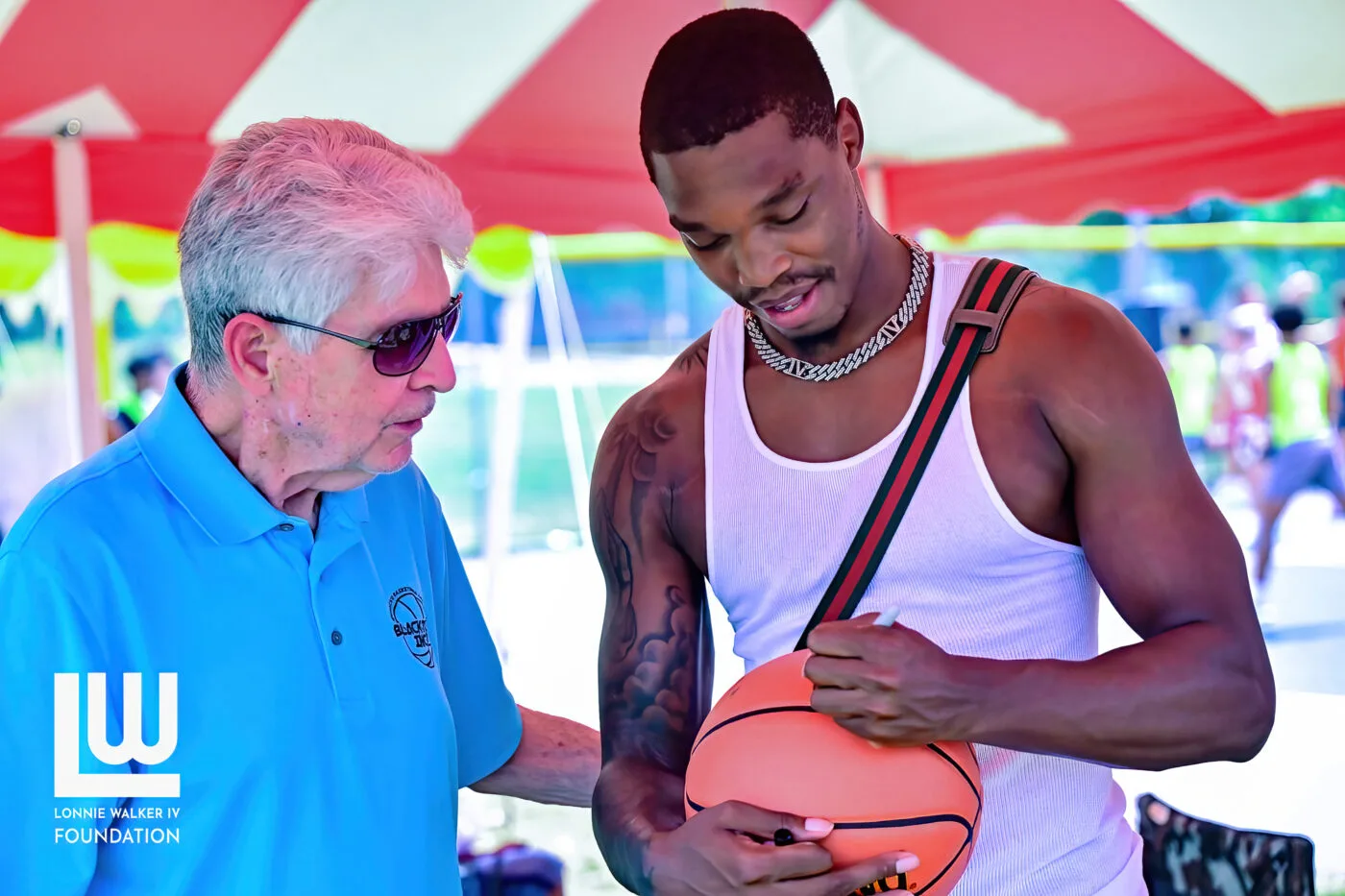 Lonnie Walker IV signing a basketball for a supporter at a community event