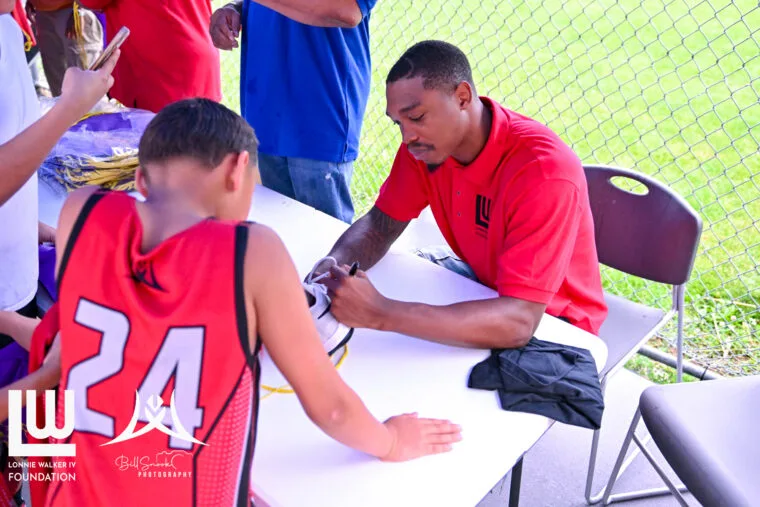 Lonnie Walker IV signing a shoe for a young fan