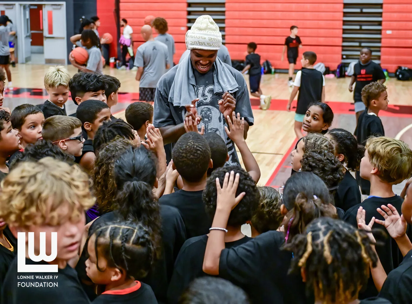 Campers crowding around Lonnie Walker IV in the gym