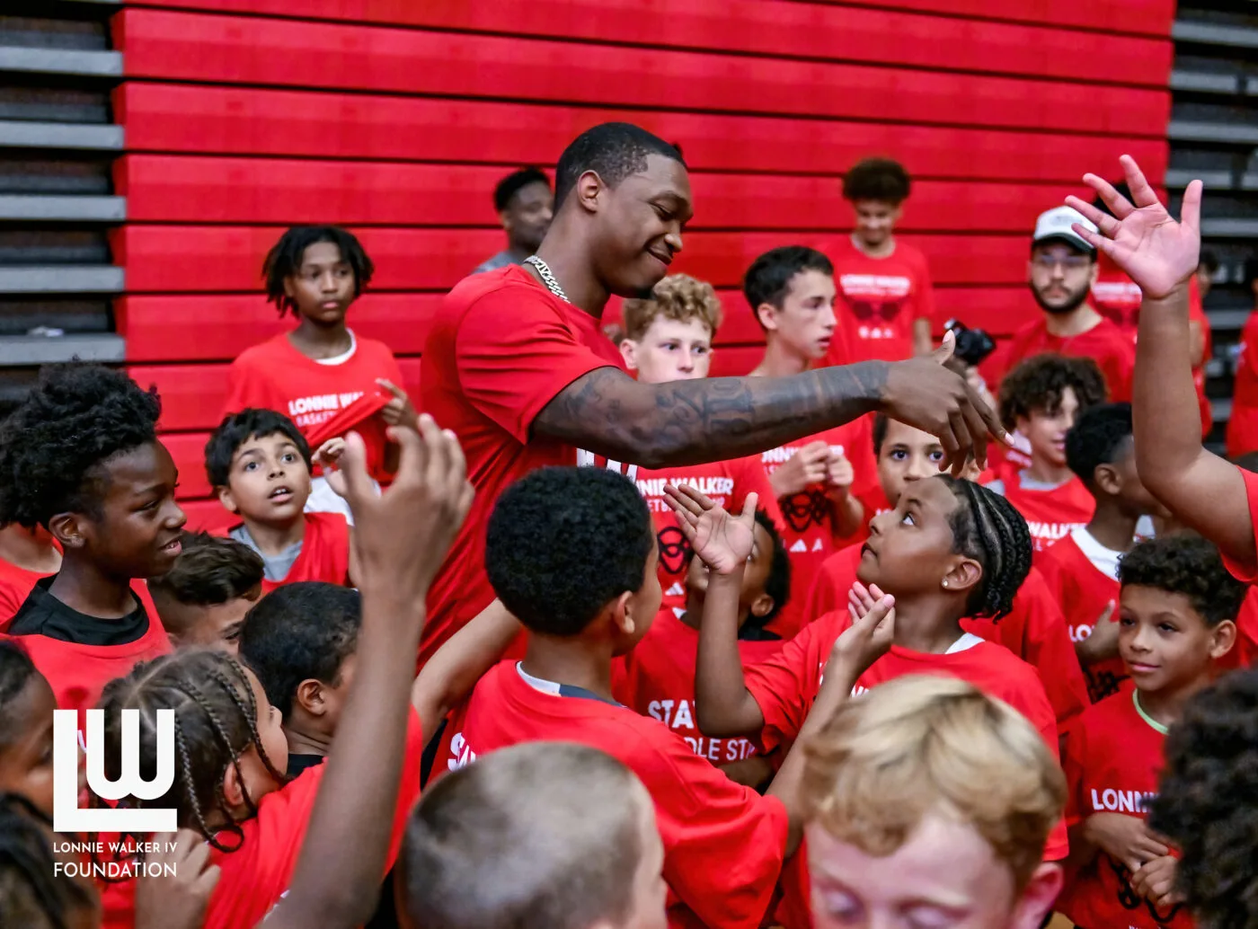 Lonnie Walker IV surrounded by campers in Foundation camp shirts