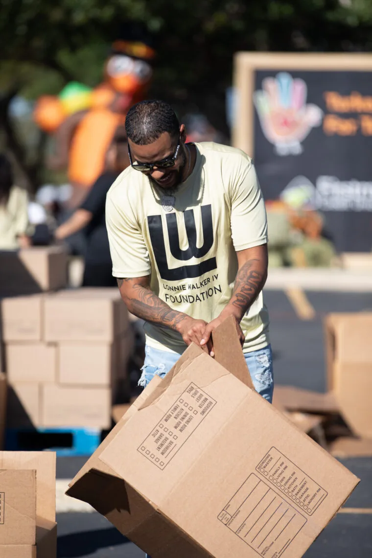 A volunteer carrying a box of Thanksgiving meal essentials