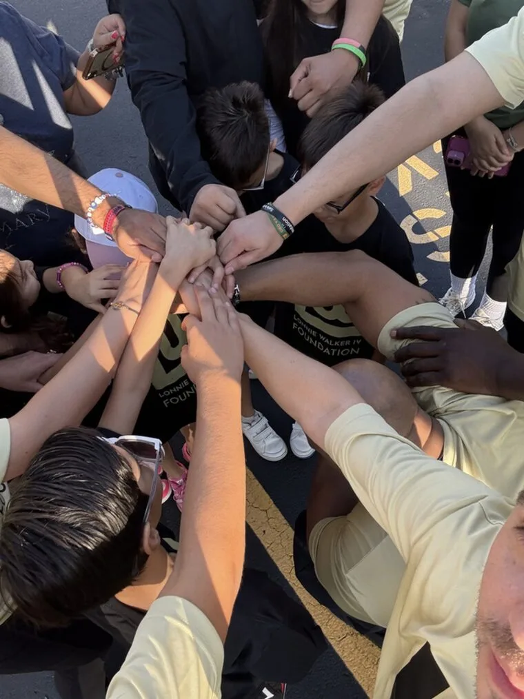 Campers putting their hands together in a team huddle