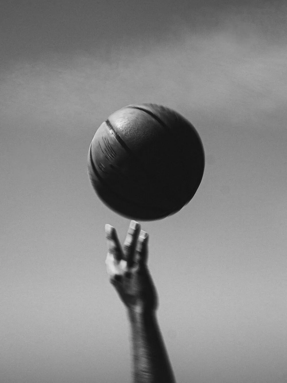 A hand palming a basketball against the sky